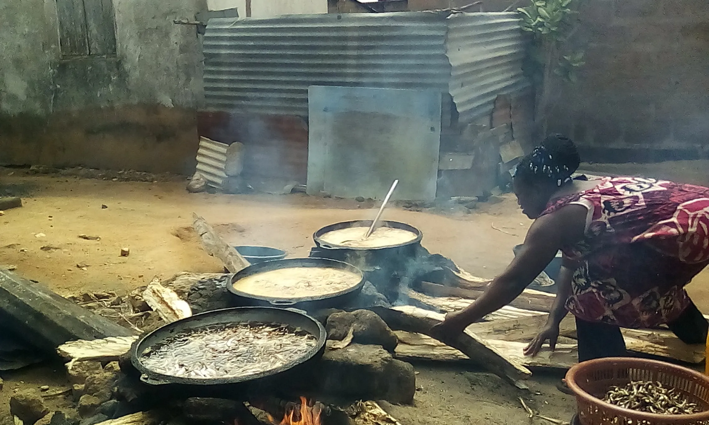 Miss Mavis Amisah, frying fish for school meals on open fire at a basic school.
