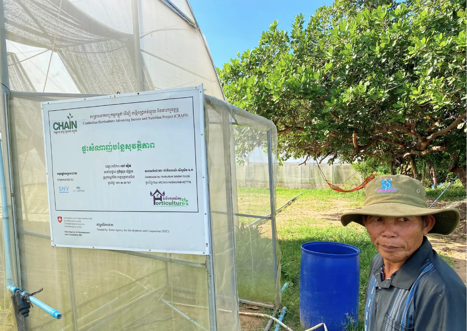 Mr. Yum standing next to a greenhouse