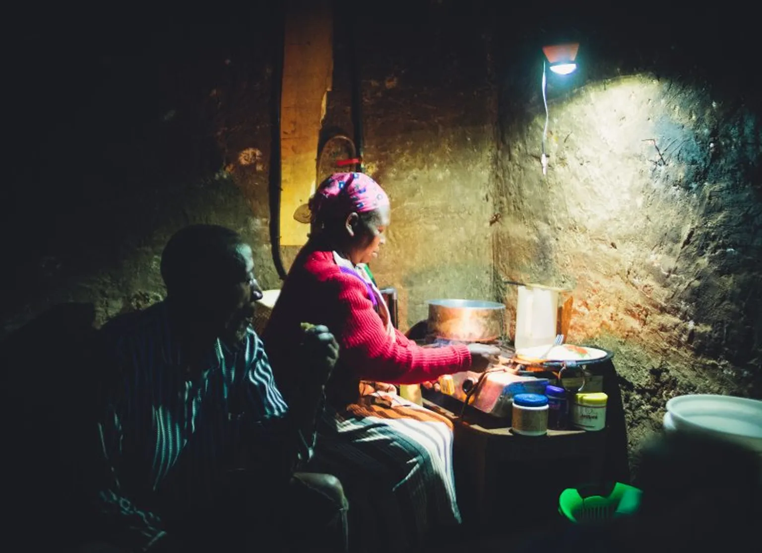 Woman in Kenya cooking by the light of a biogas lantern