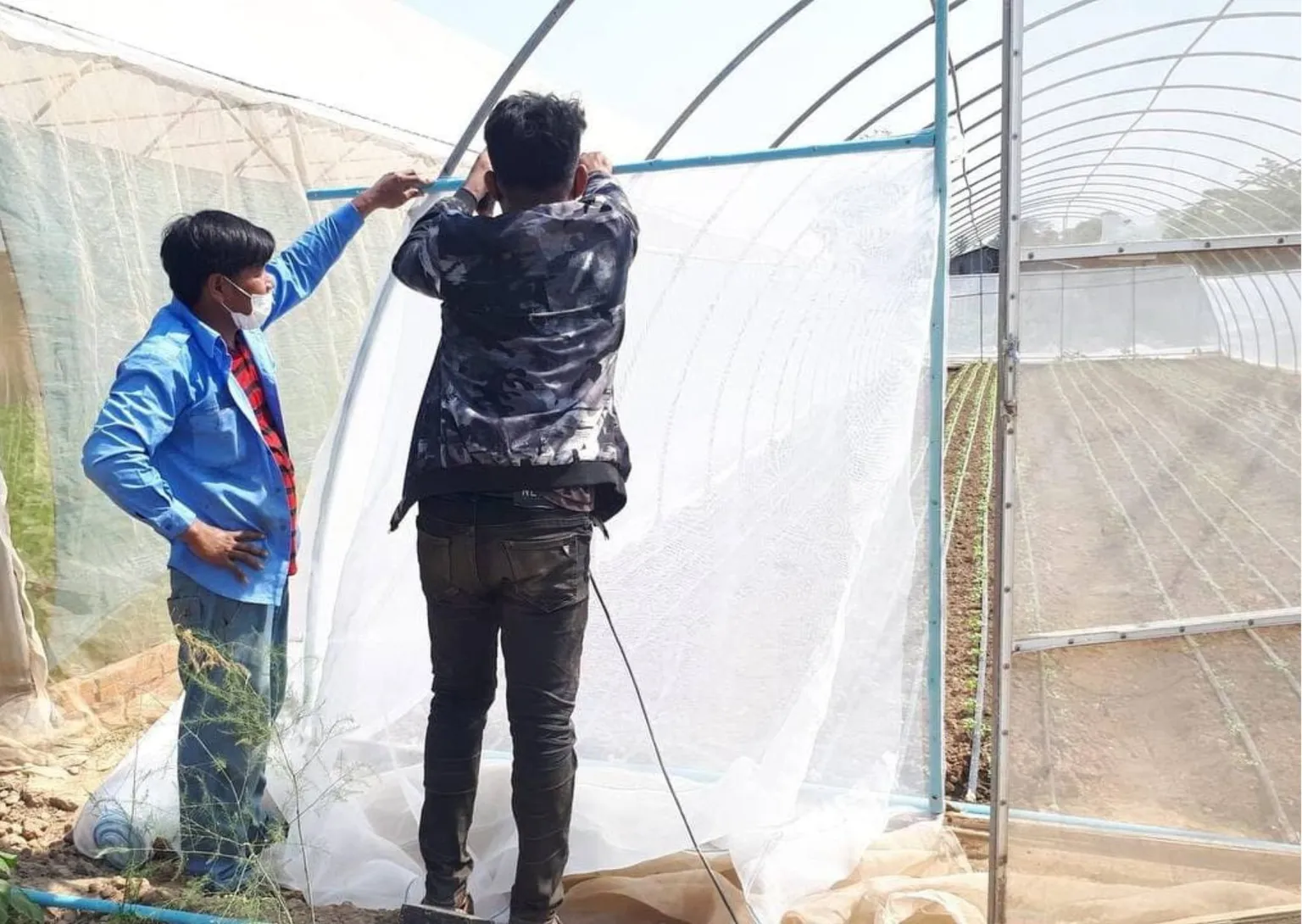 Two men repair greenhouses in Cambodia