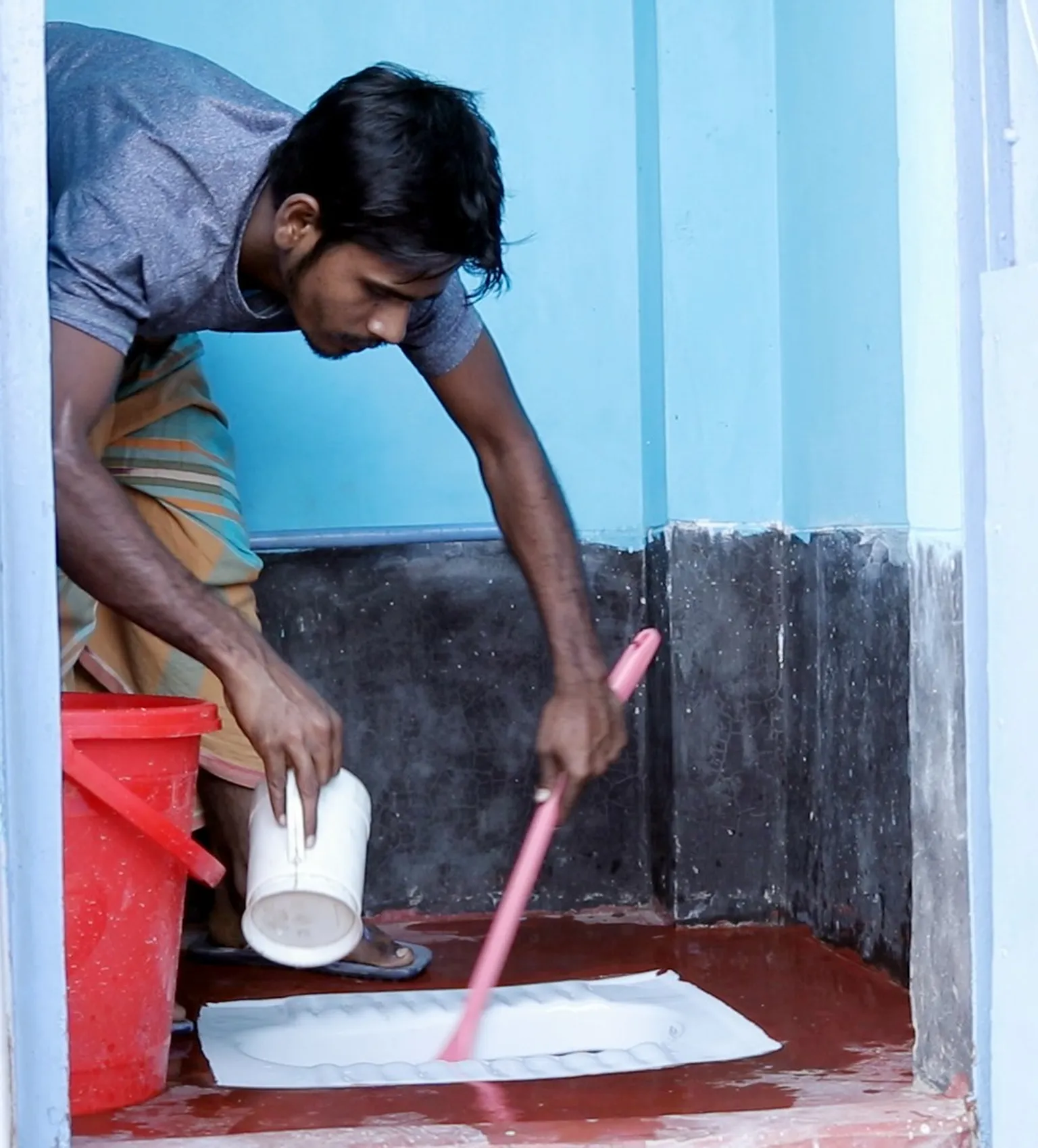 Toilet management committee member maintains public toilet in slum area in Bangladesh