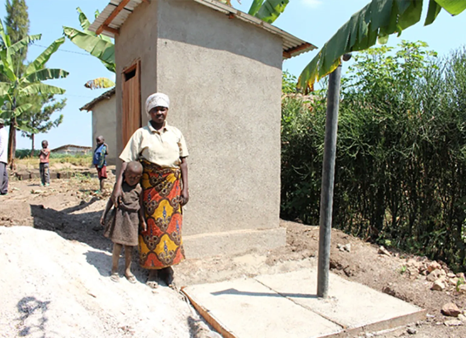 Ms. Nyiranyezimana with her daughter next next to the newly constructed latrine