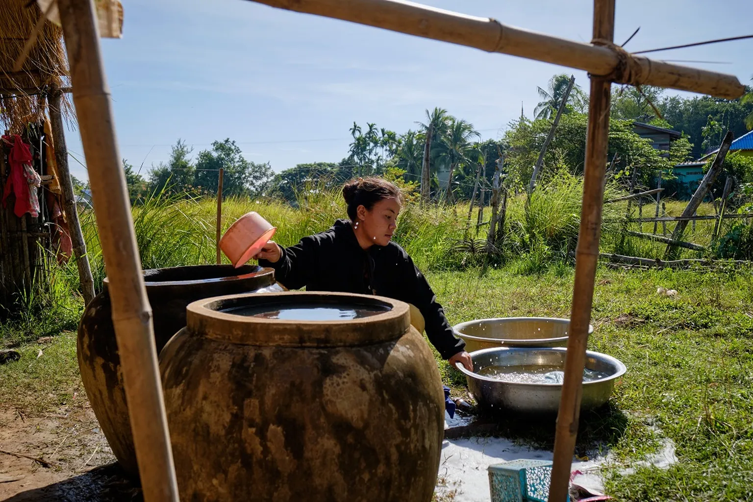 Champhone district resident drawing water stored in container (Bart Verweij for SNV)