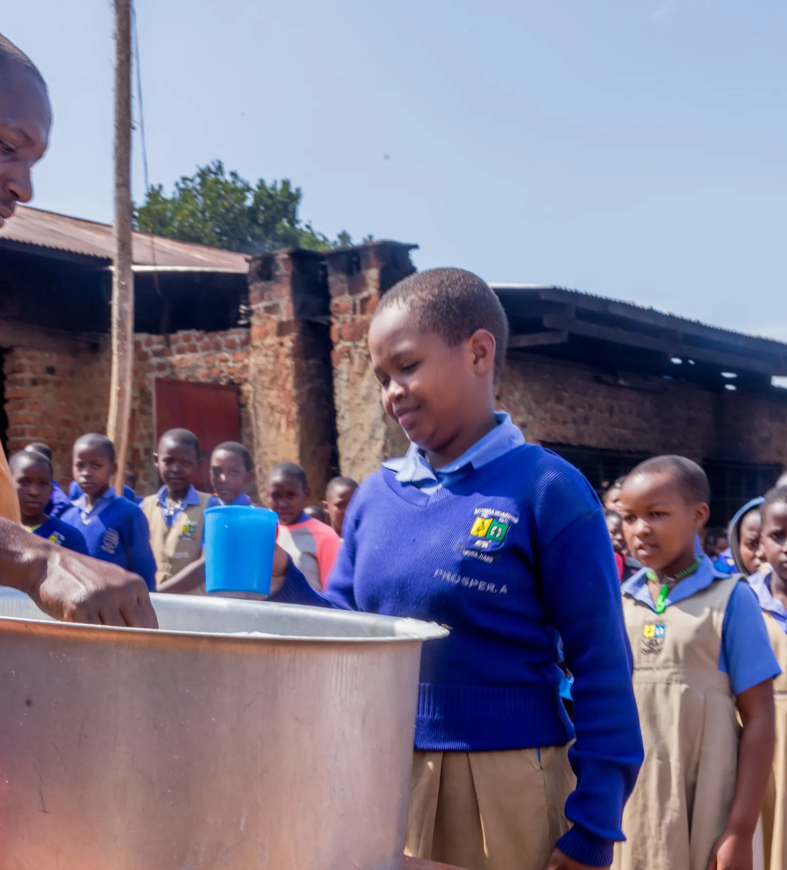 A girl in a queue to have a school meal as part of the TIDE programme in Uganda