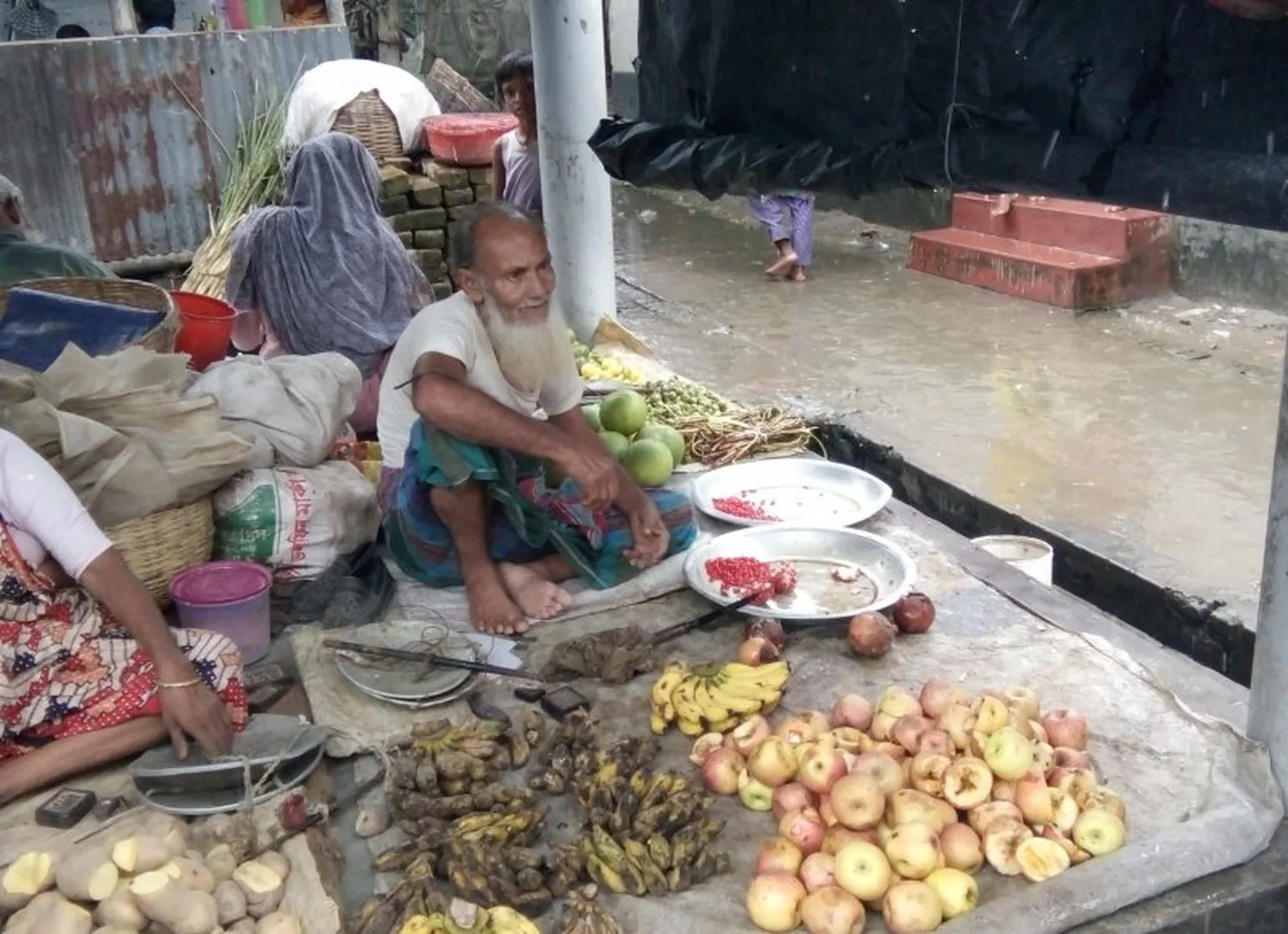 A vendor at an informal market selling cheap gone-off fruit and vegetables