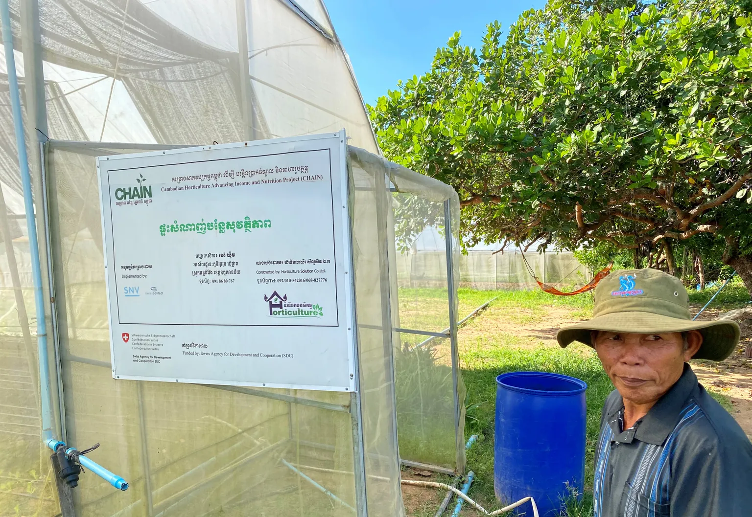 Mr. Yum standing next to a greenhouse