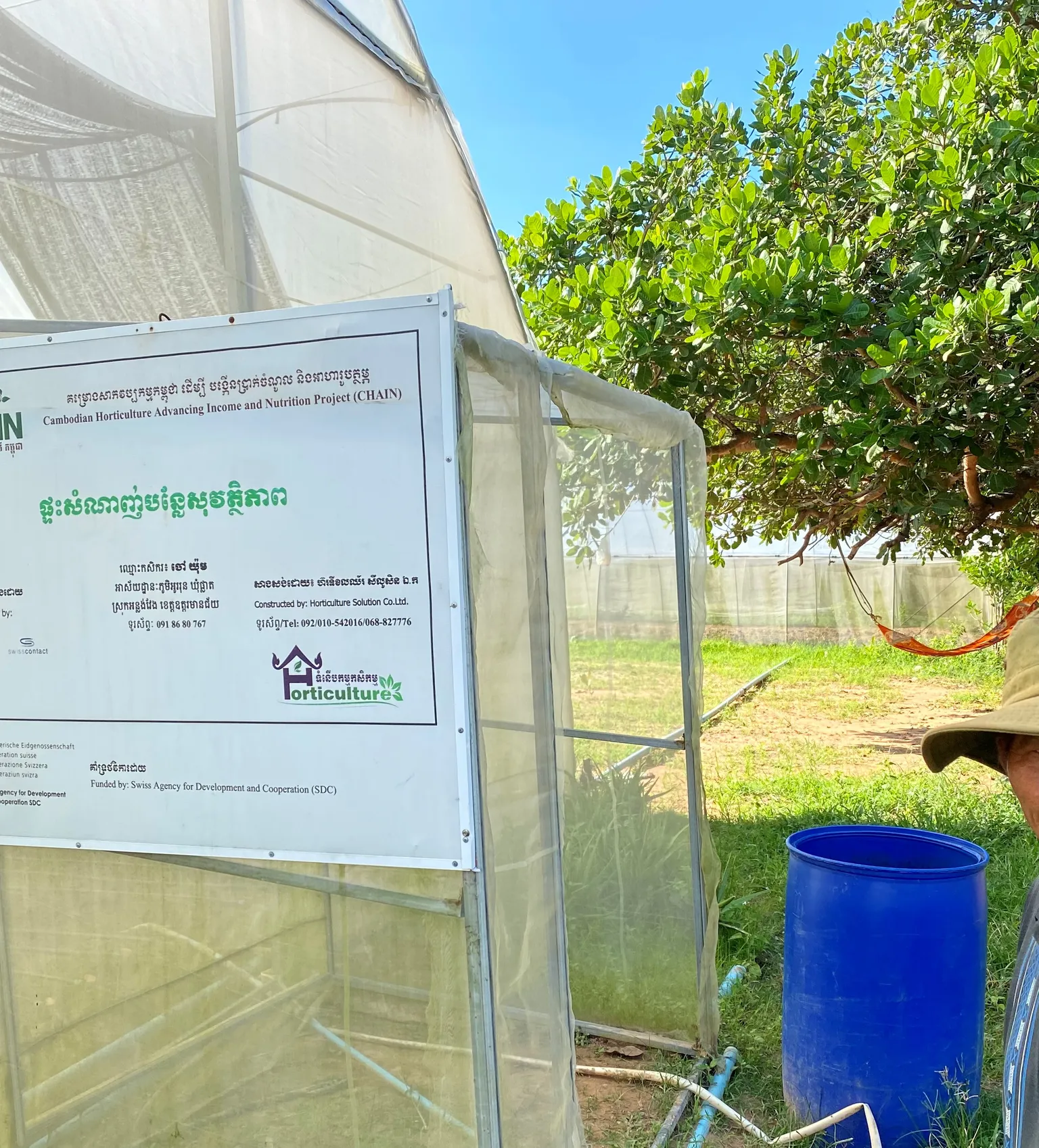 Mr. Yum standing next to a greenhouse