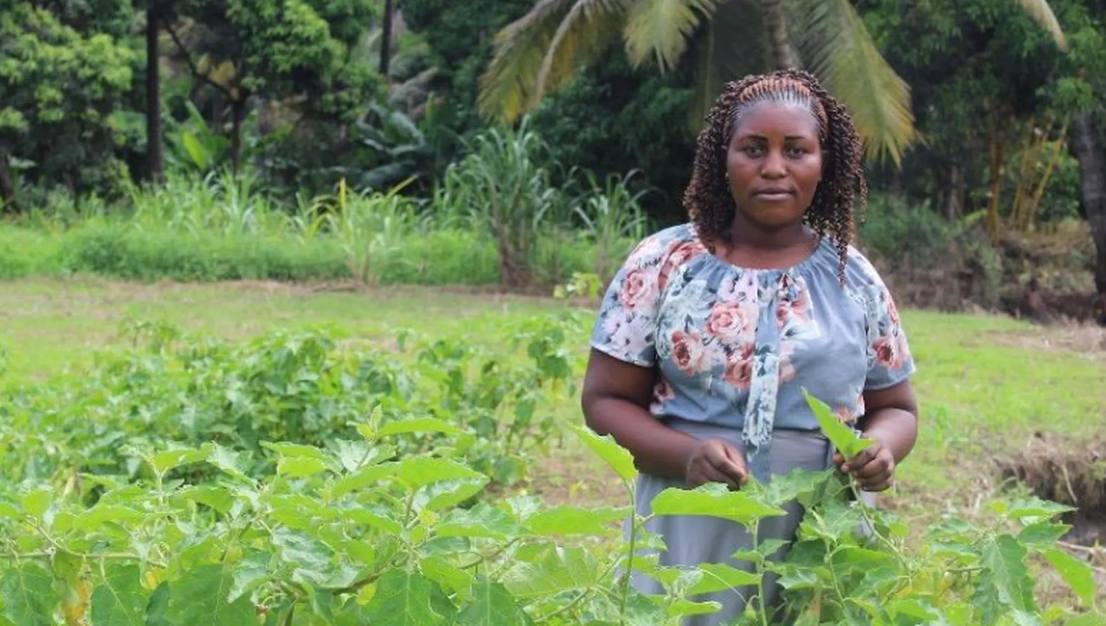 Young woman is pictured standing in front of greenery