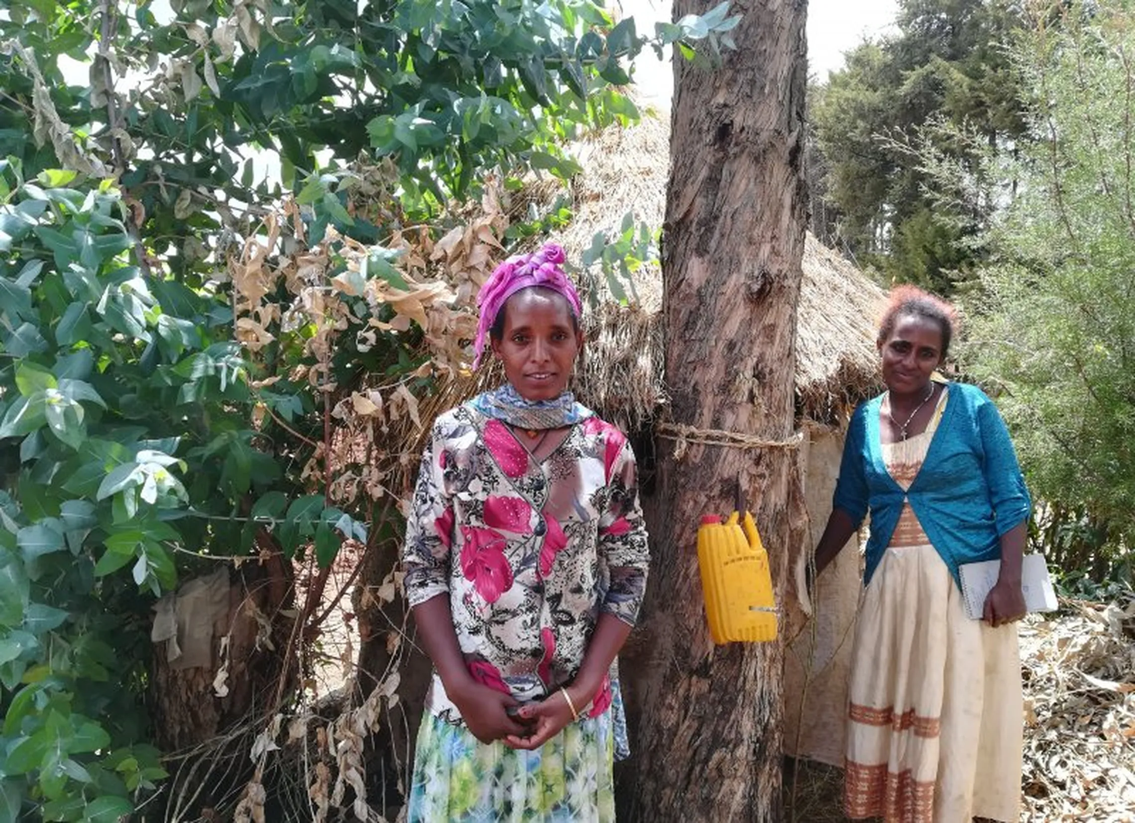 Agin Ben (L) posing in front of her latrine, with health extension worker (R).