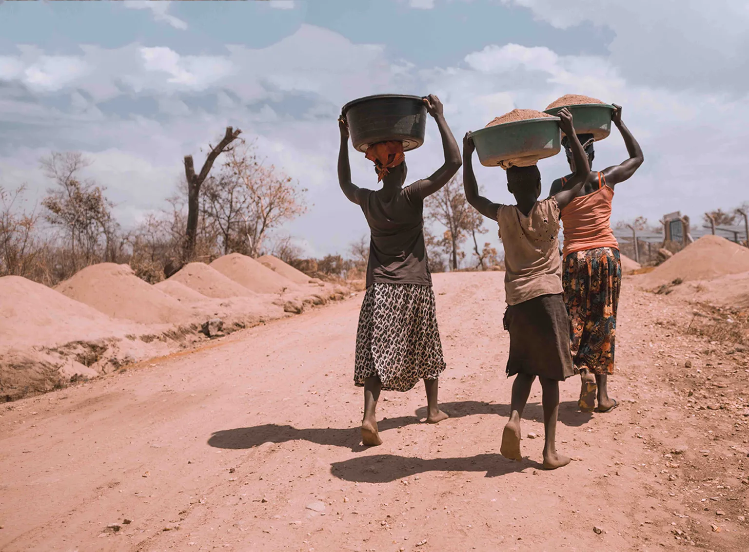 Women carrying buckets with sand on head