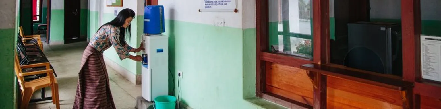 Lady taking water from a dispenser.