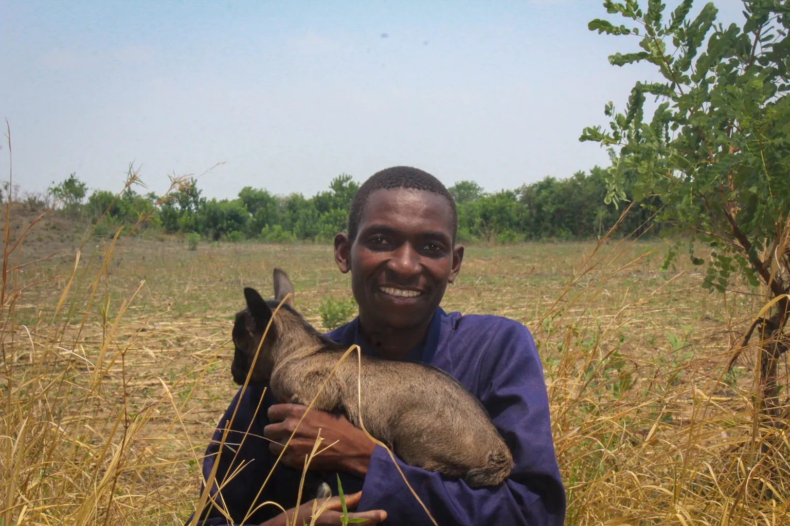 Gift Mubanga holds a goat in his arms while posing for a photo