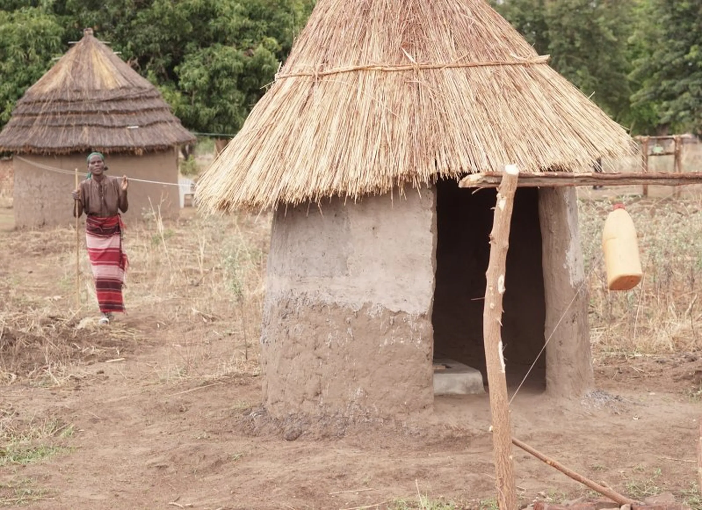 A woman with sight impairment uses a string guide to reach the latrine