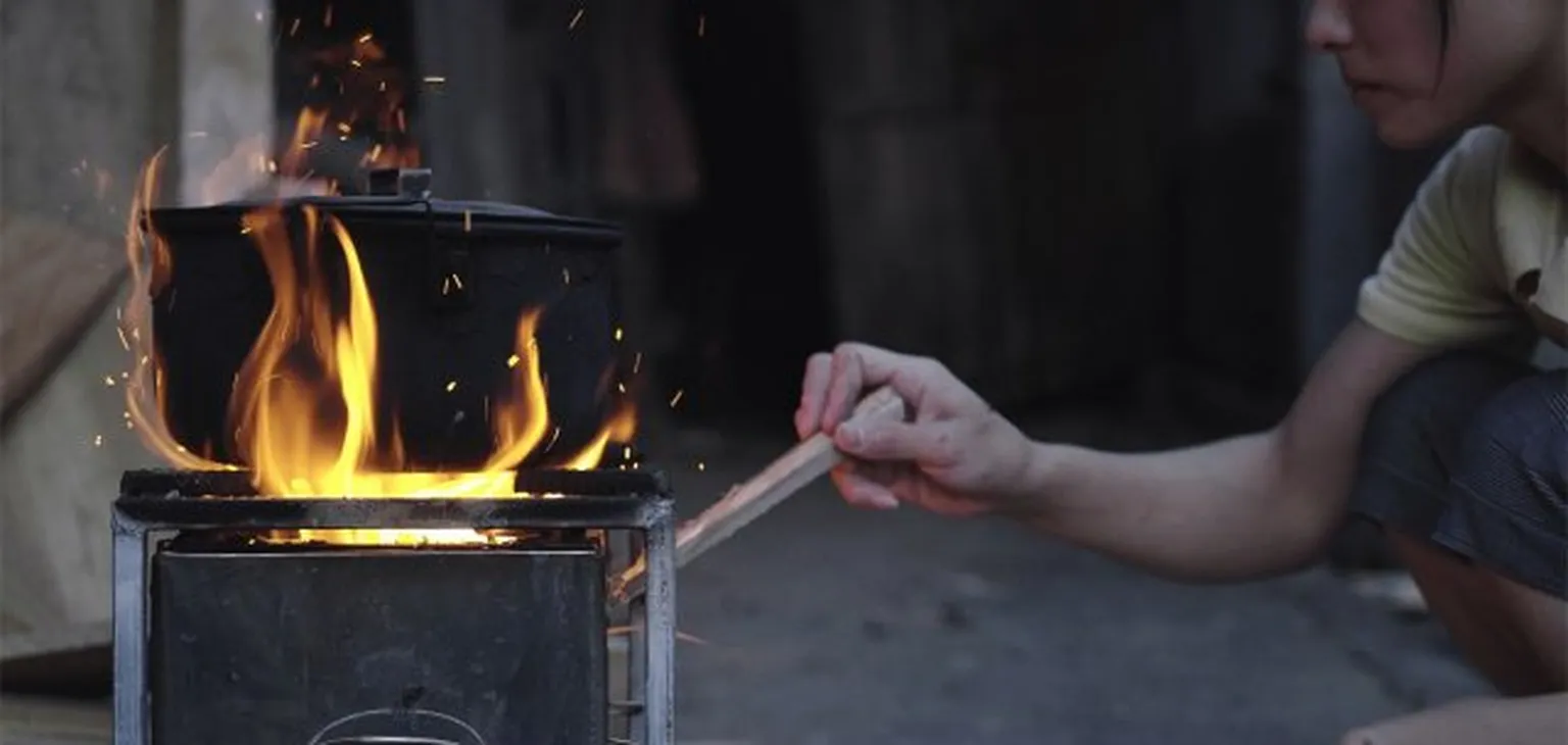 working stone with fire underneath and a woman adding wood under it