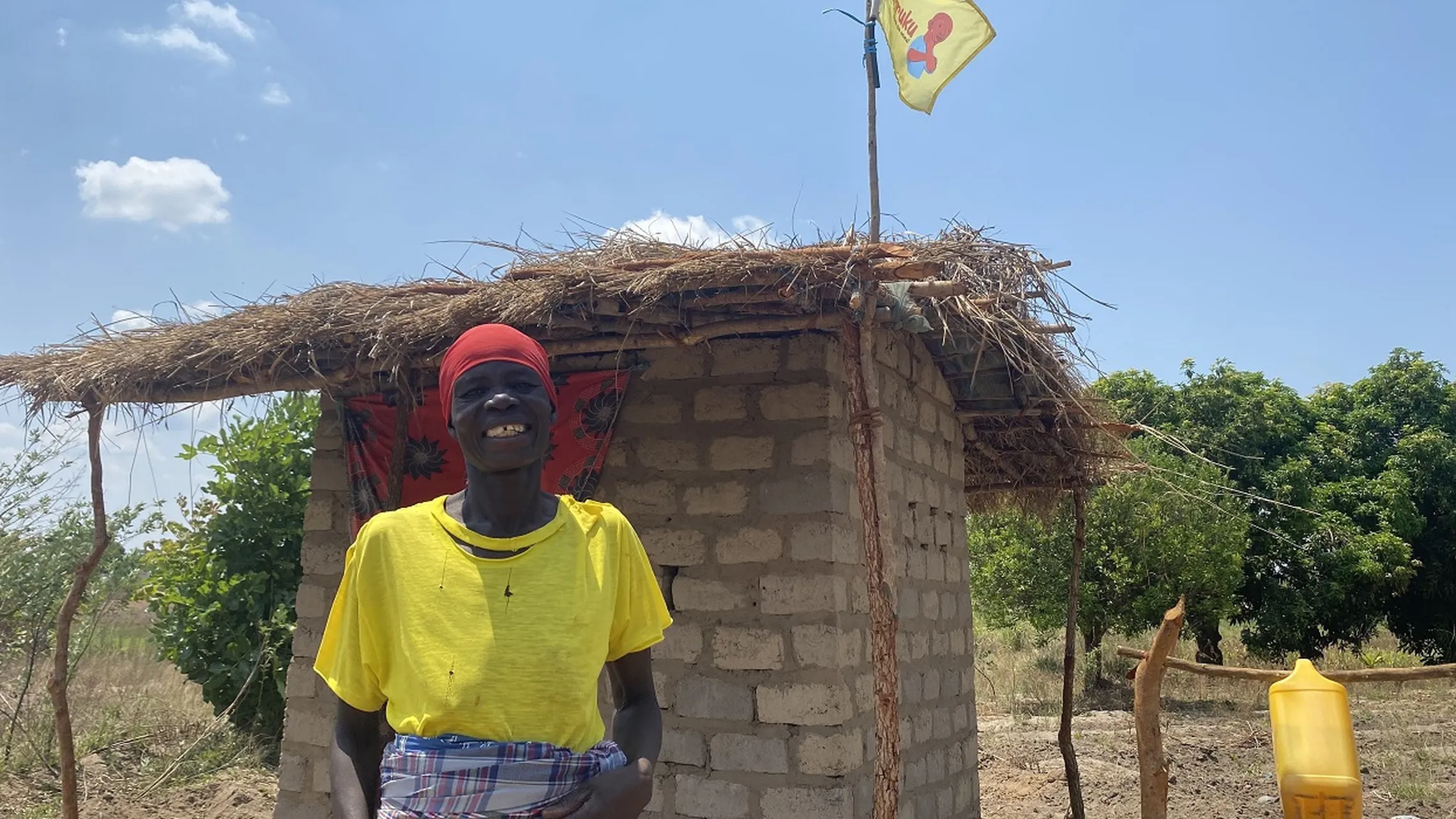 Smiling woman in front of her newly built toilet