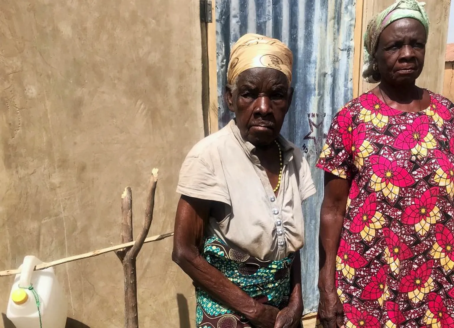 Catherine and her 89-year old mother standing next to their handwashing facility