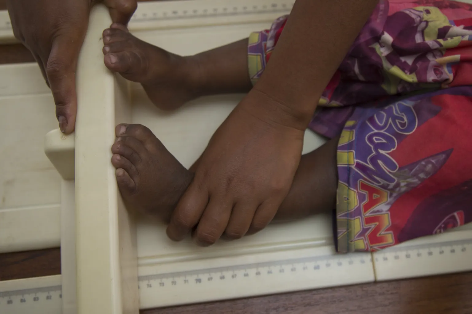 baby feet are being carefully held to measure the height of the small child