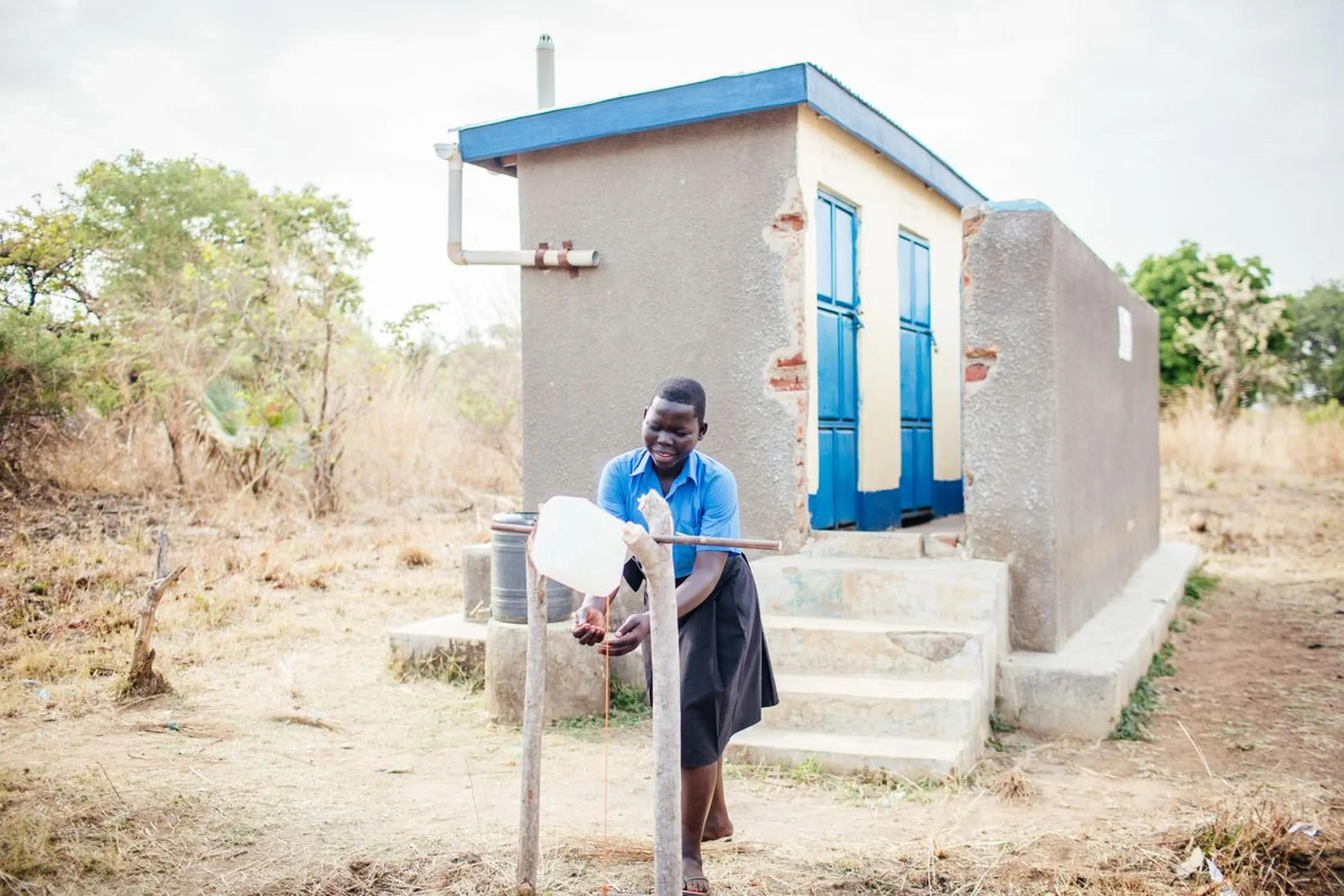 A schoolgirl washing her hands using a pedal washing station after using the latrine.